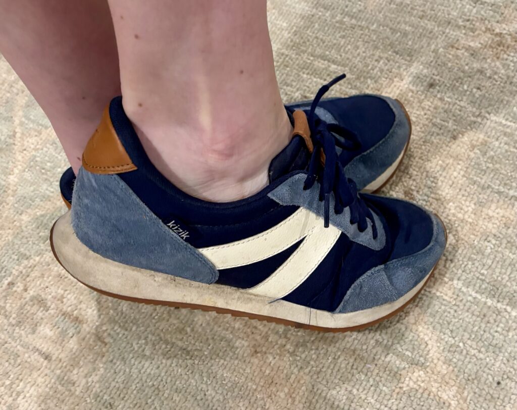 Close-up of Kizik shoes being worn, showcasing a navy and gray design with a white stripe on the side, an easy product for family travel.